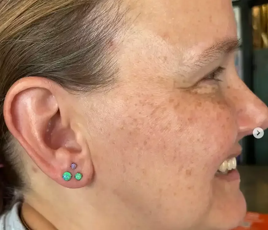Stacked earlobe piercings 2 healed earlobe all titanium 1 purple opal threadless end 2 green opal threadless ends and threadless labret posts done by Amber Paje of James River Tattoo in Carrollton VA