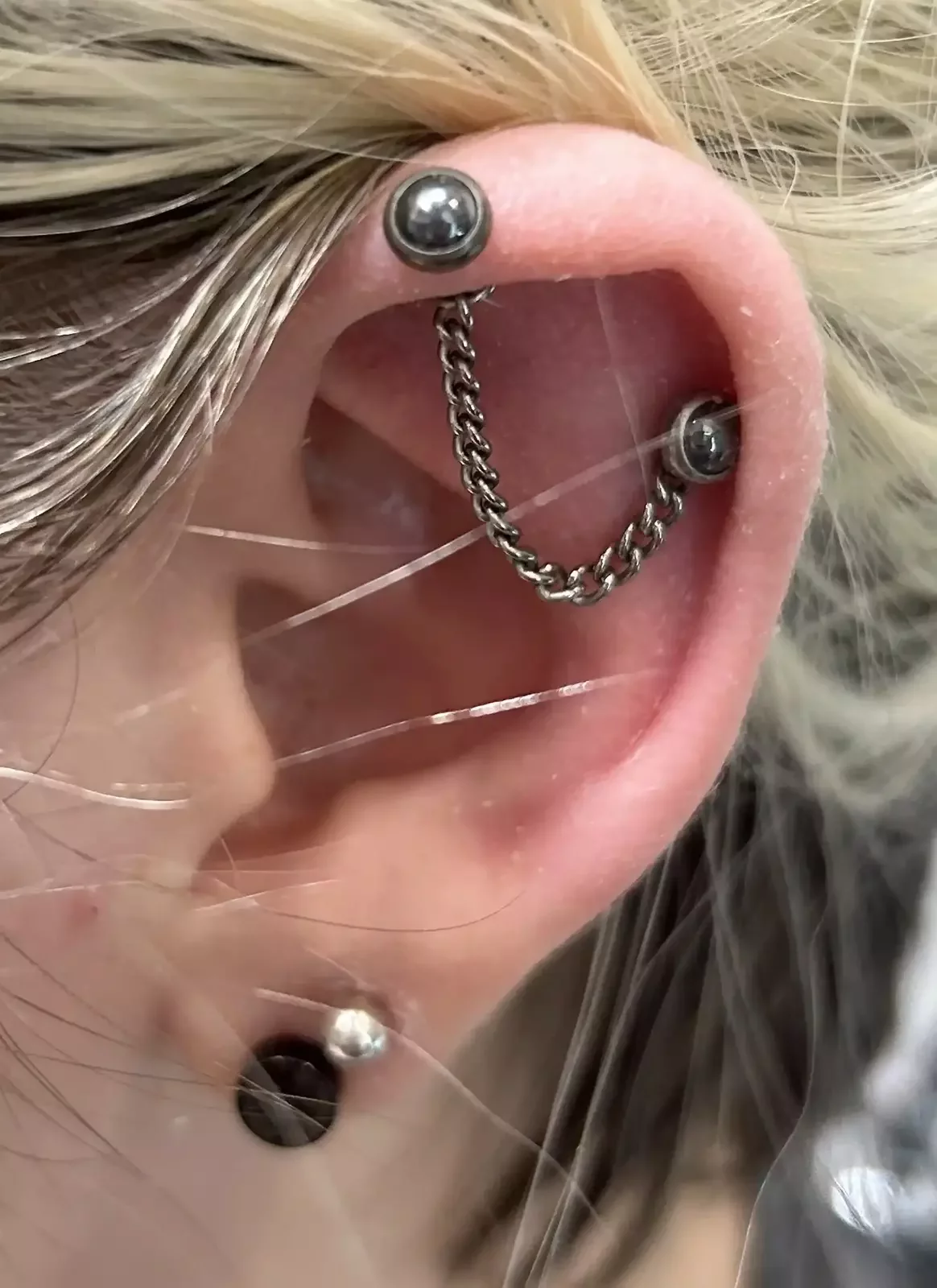 Ear curation hematite cabochon threadless ends on threadless labret posts and a titanium chain threaded into piercings on a helix and a helix flat by Amber Paje of James RiverTattoo in Carrollton VA